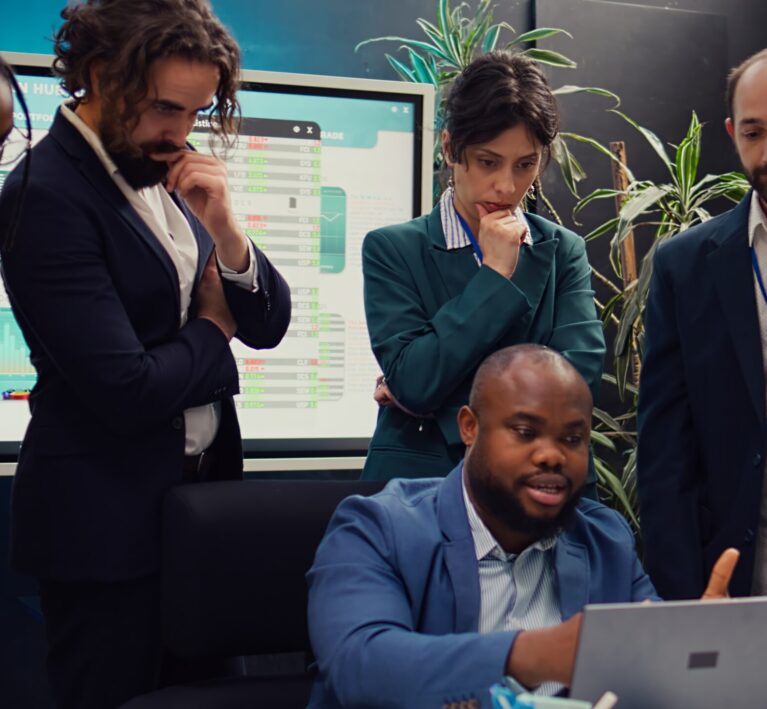 Diverse corporate employees analyzing project updates to ensure goal accomplishment, reviewing infographics on laptop and finding ways to obtain new funds. Business management team. Camera B.